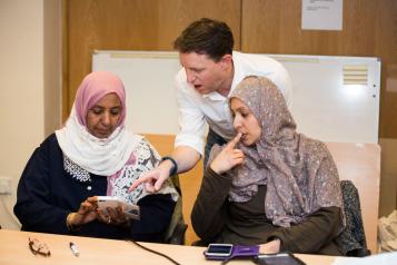 Two women and a man looking at a mobile phone