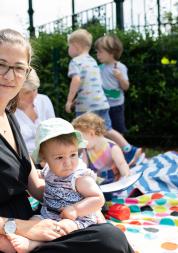 Woman sitting on a picnic blanket with her baby